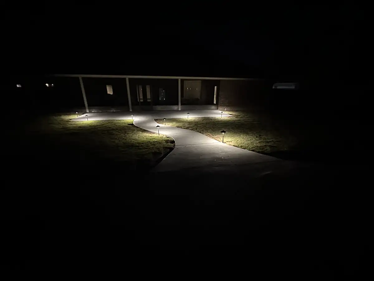 Warm landscape lighting grazing a stone wall and nearby planting